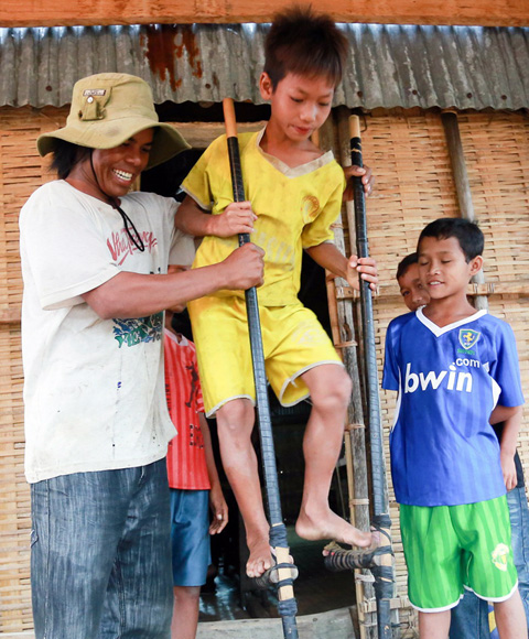 Dinh Lek, the best stilt performer in the village, teaches children how to use stilts.