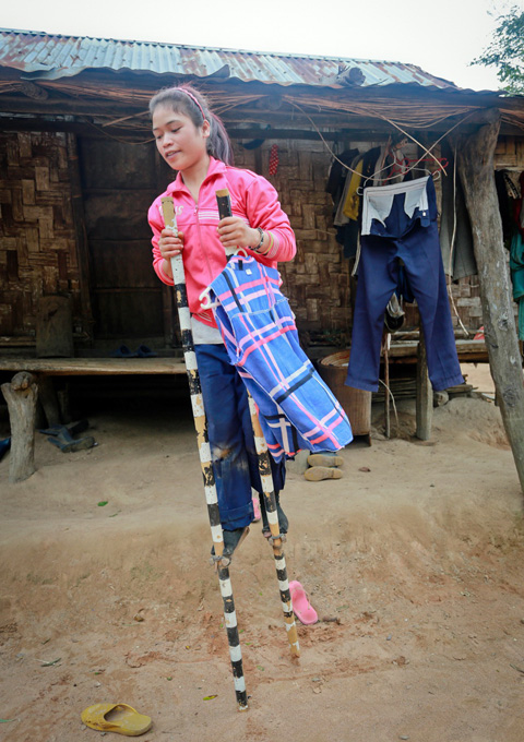 Local girl Dinh Thi Ploi walks on stilts to hang out the washing.