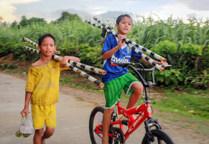 Two little boys Dinh Buon (R) and Dinh Tiep bring stilts to an empty land in the village where they practice walking on stilts.