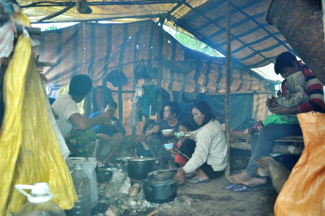 A family is seen eating in a tent.