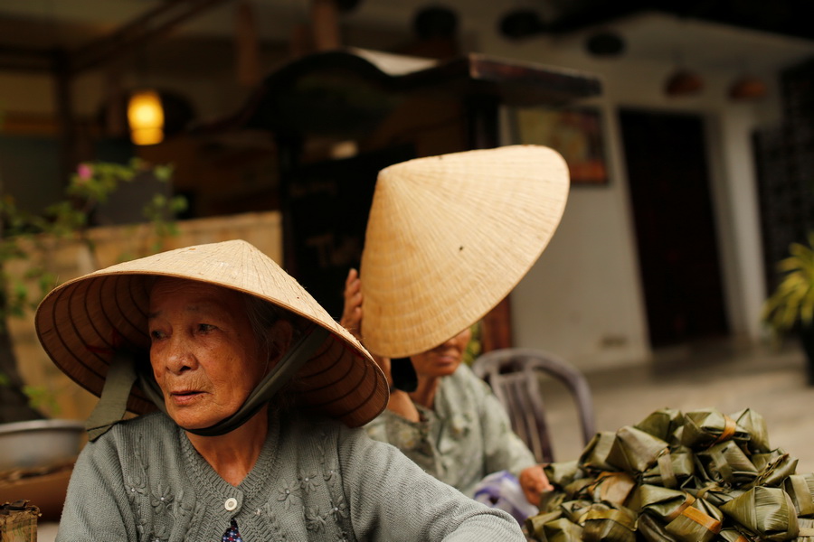 Women wearing traditional hats, known as non la, sit in a market in Hoi An, Vietnam April 5, 2016.