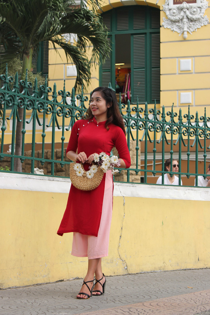A woman dressed in the modern ao dai poses for photographs in front of the Saigon Central Post Office. Photo: Tuoi Tre