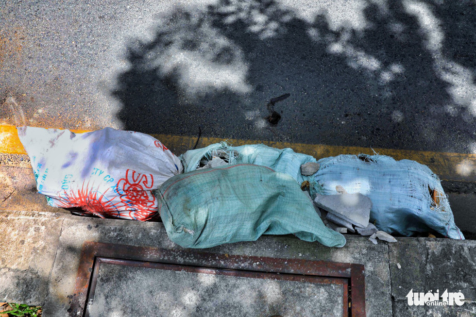 Garbage, along with a broom, is dumped at a sewer on Trinh Hoai Duc Street in Binh Thanh.