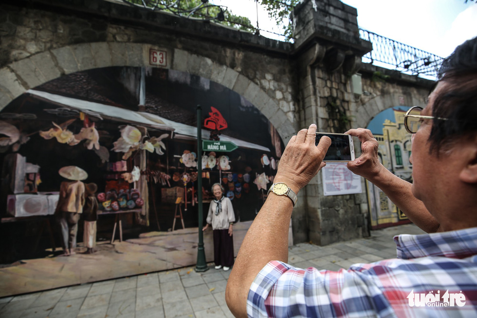 Tourists take photos next to a mural wall in Phung Hung Street in Hoan Kiem District, Hanoi. Photo: Tuoi Tre