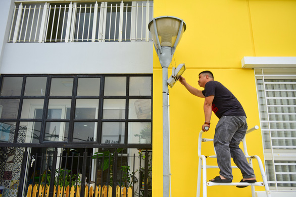 A man repairs a light within the apartment complex. Photo: Tuoi Tre