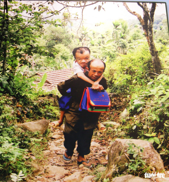 A photo of Pham Viet Tuong, 28 years old, an AO sufferer in the central Vietnamese province of Quang Nam, piggybacked to school by his father on display at the exhibition. Photo: Tuoi Tre