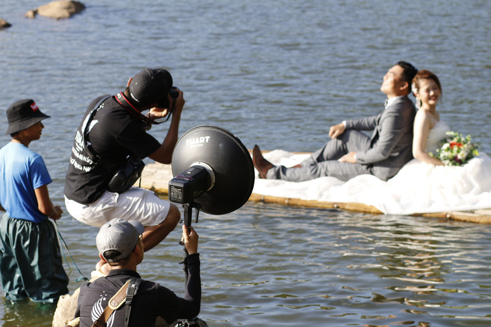 A team of photographers take wedding photos of a couple at the Green Lake in Son Tra Peninsula, Da Nang. Photo: Tuoi Tre