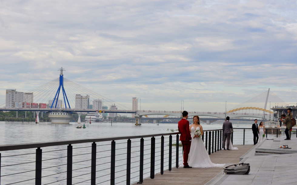 Three couples pose for their wedding photos at a bank along the Han River in Da Nang. Photo: Tuoi Tre