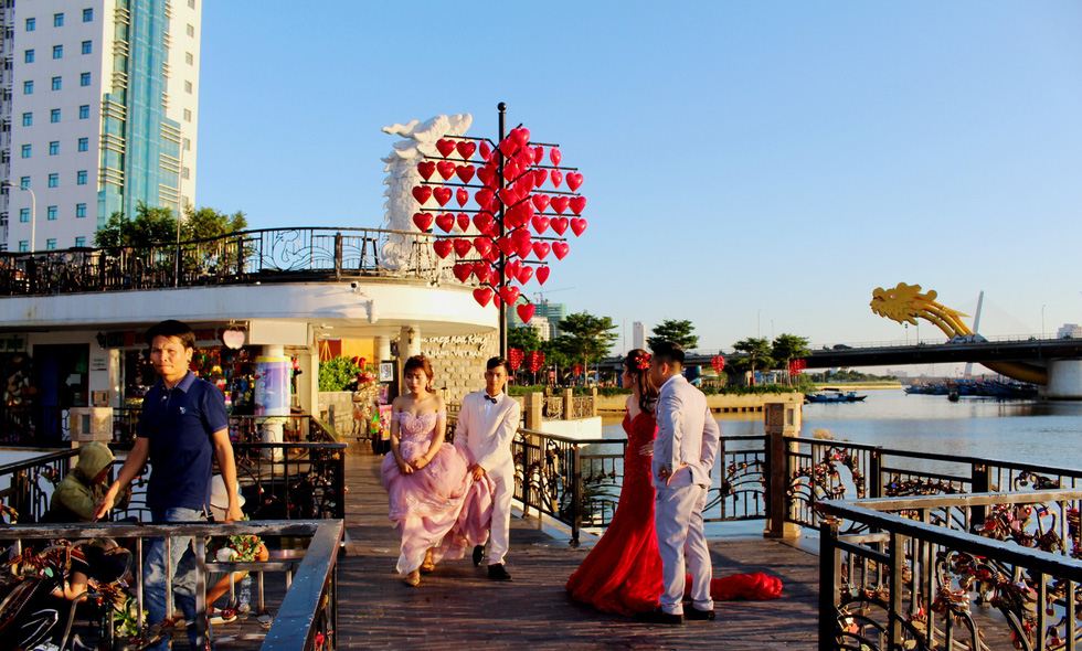 Two couples prepare for their photo shoot at the “Love Lock” Bridge in Da Nang. Photo: Tuoi Tre