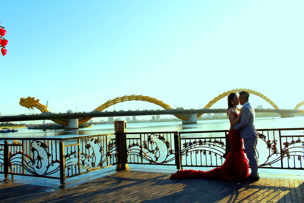 A couple poses for their wedding photo at a bank opposite the Dragon Bridge in Da Nang. Photo: Tuoi Tre