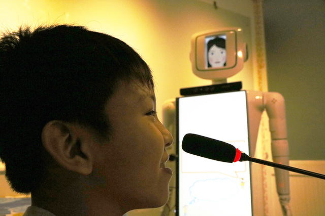 A child talks with Nguyen Tran Thanh Phong’s robot via a wireless microphone. Photo: Tuoi Tre