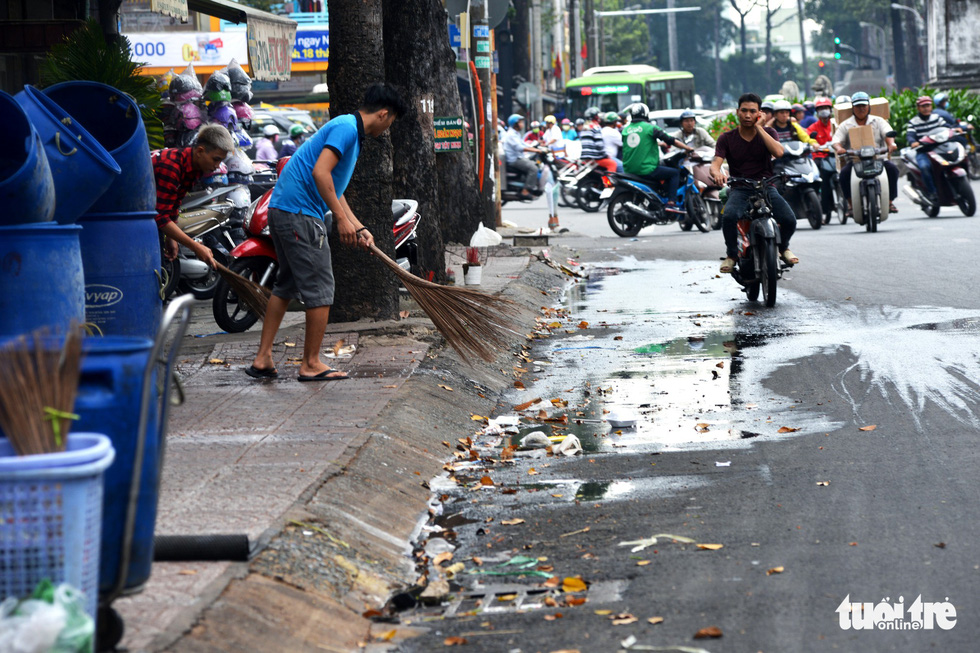 Employee of a diner sweeps trash and leftover food onto the roadway on Nguyen Tri Phuong Street in District 10.