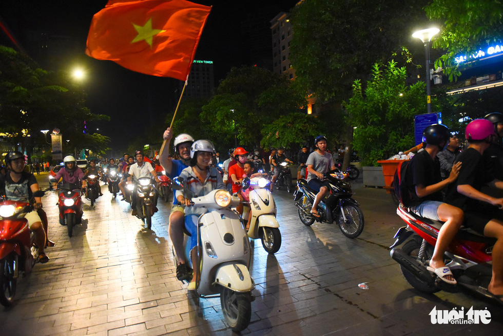 A foreign man and a Vietnamese woman join the crowd of people on motorbikes touring around the Nguyen Hue pedestrian area on November 16, 2018. Photo: Tuoi Tre