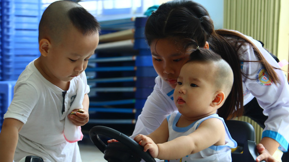 A student plays with two babies at the Quan Am Pagoda in Vinh Long Province, southwestern Vietnam. Photo: Tuoi Tre
