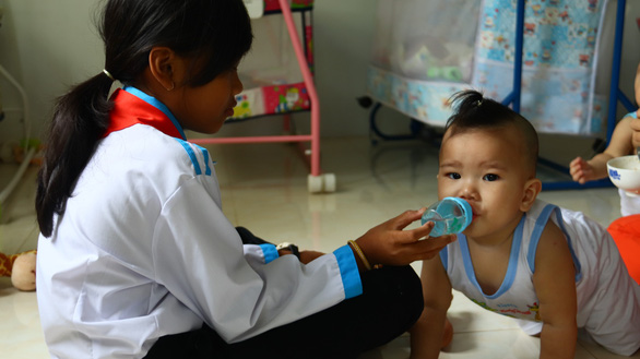 A student bottle-feeds a baby at the Quan Am Pagoda in Vinh Long Province, southwestern Vietnam. Photo: Tuoi Tre