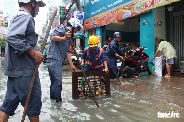 Employees of the Urban Drainage Company dredge a manhole to mitigate inundation. Photo: Tuoi Tre