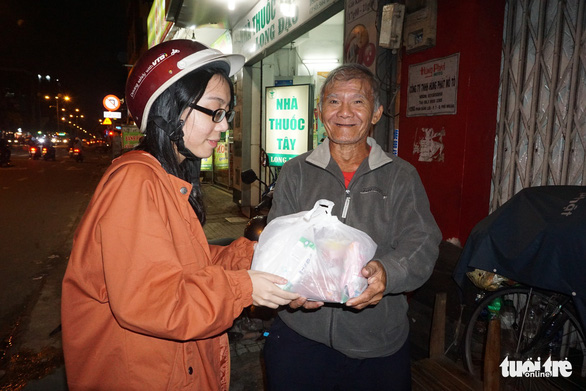A woman gives a gift to a homeless man in Ho Chi Minh City, Vietnam. Photo: Tuoi Tre