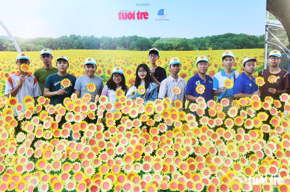 Participants pose for a photo with paper sunflowers prepared by volunteers.