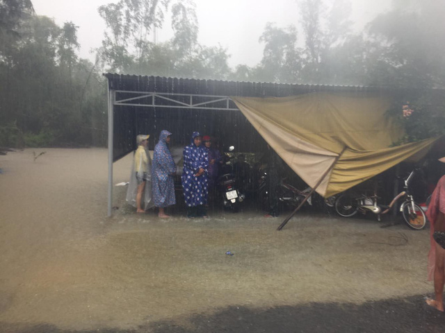 Motorcyclists take shelter as the road to their homes was submerged by water in Quang Nam Province, central Vietnam, December 10, 2018. Photo: Tuoi Tre