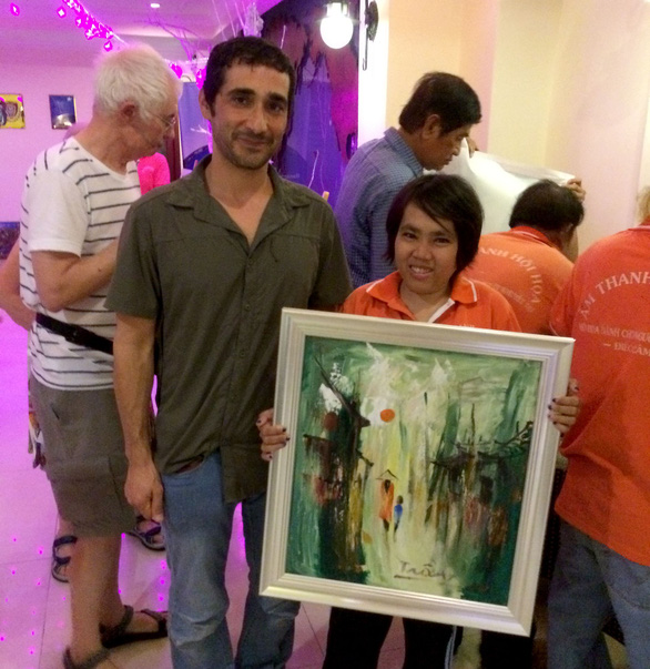 A child from Van Y’s class holds her painting, bought by Tal Ben Shlomo, a Jewish painting collector standing beside her. He describes her as a talent in painting. Photo: Tuoi Tre