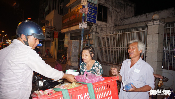 Vo To Phuong hands a box of rice and grilled pork to people in difficult situations along Phan Dang Luu Street in Ho Chi Minh City, Vietnam, December 24, 2018. Photo: Tuoi Tre