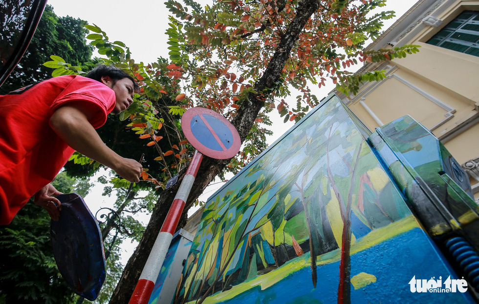 A Hanoi Art Space member paints an electric cabinet on Trang Thi Street. Photo: Tuoi Tre
