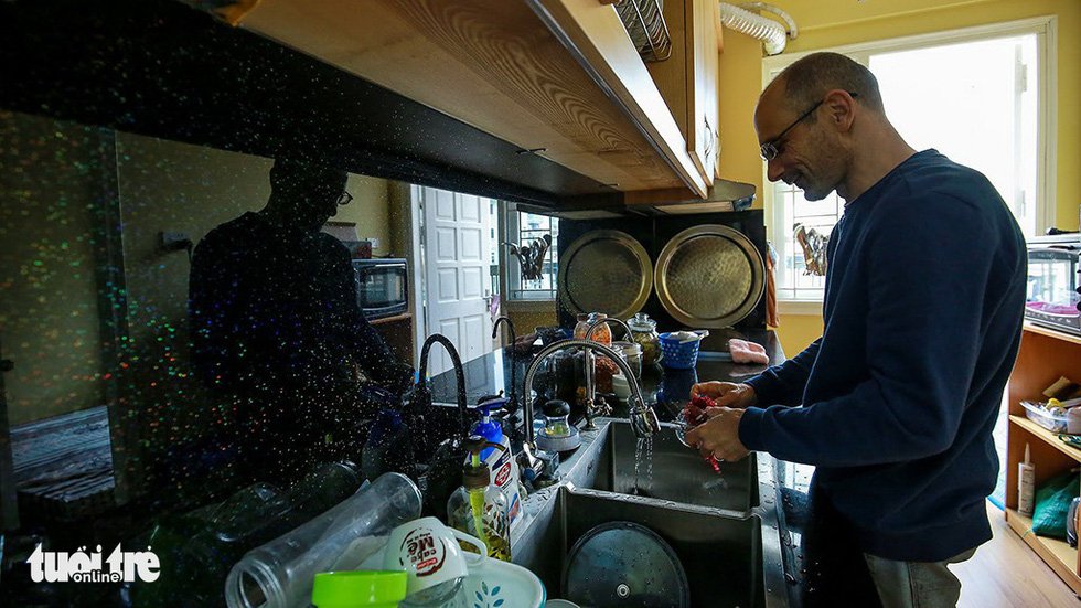 Neil Bowden Laurence washes the dishes in the couple’s kitchen. Photo: Tuoi Tre