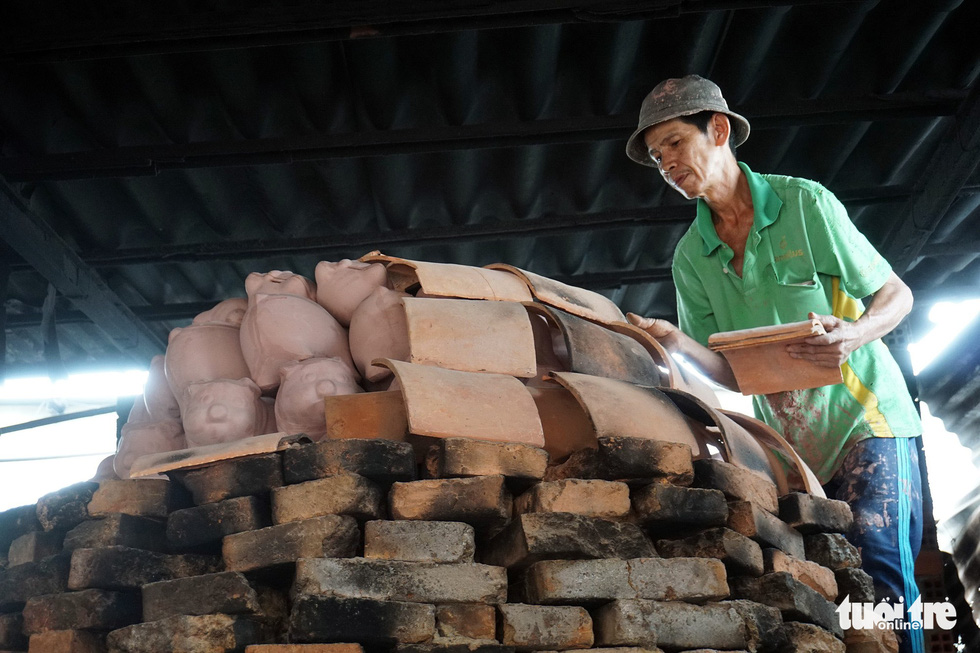 A man puts tiles on clay piggy banks as they are baked in Binh Duong Province, southern Vietnam. Photo: Tuoi Tre