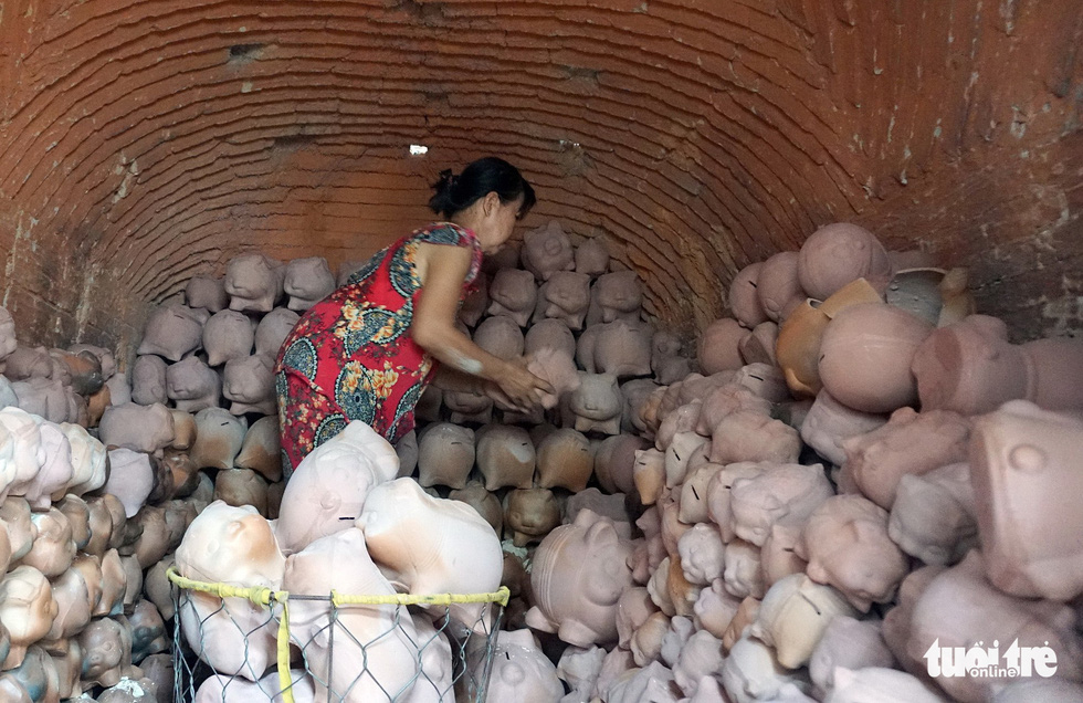 A woman takes baked piggy banks from an oven in Binh Duong Province, southern Vietnam. Photo: Tuoi Tre