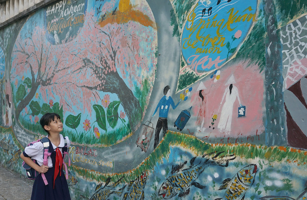 A student looks at a mural made by Nguyen Van Minh along an alley in Ho Chi Minh City, Vietnam. Photo: Tuoi Tre