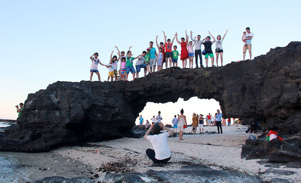 Tourists take a group photo on top of the To Vo Arch in Ly Son, Quang Ngai Province in central Vietnam. Photo: Tran Mai / Tuoi Tre