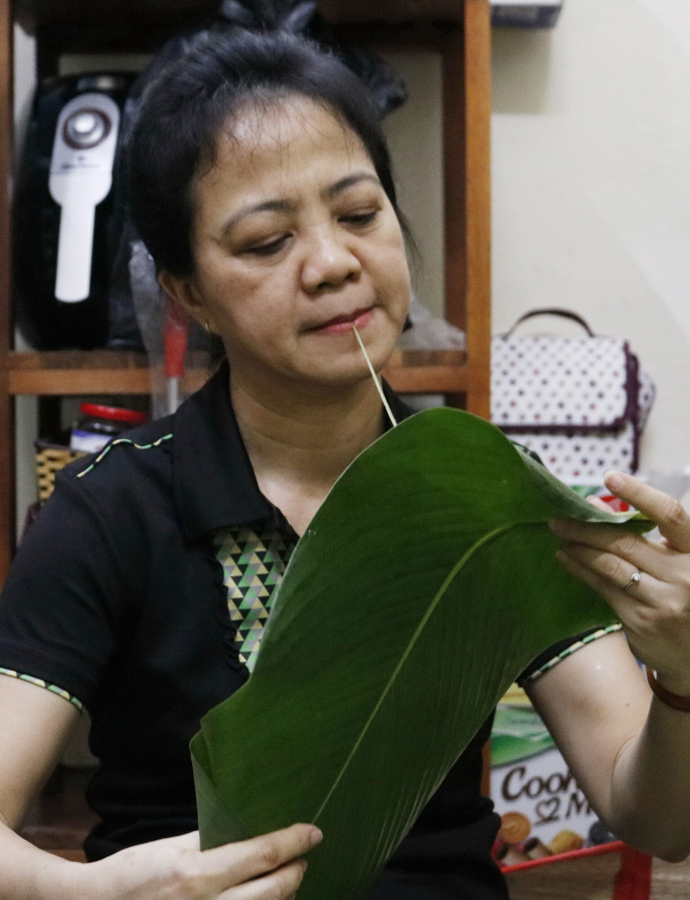Bui Thi Hong Vinh uses her mouth to remove the midrib of a stachyphrynium placentarium leaf, locally known as la dong, used for wrapping banh chung. Photo: Ngoc Phuong & Linh To / Tuoi Tre