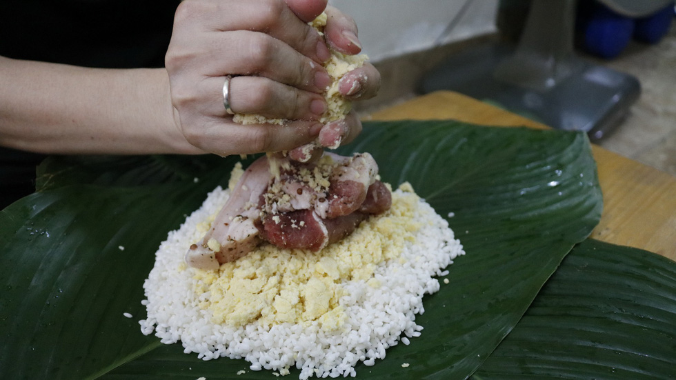 Bui Thi Hong Vinh puts pork and ground mung beans onto rice to make banh chung. Photo: Ngoc Phuong & Linh To / Tuoi Tre
