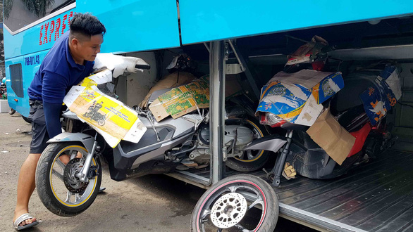 An employee loads motorbikes onto the luggage compartment of a passenger bus. Photo: Ngoc Hien / Tuoi Tre