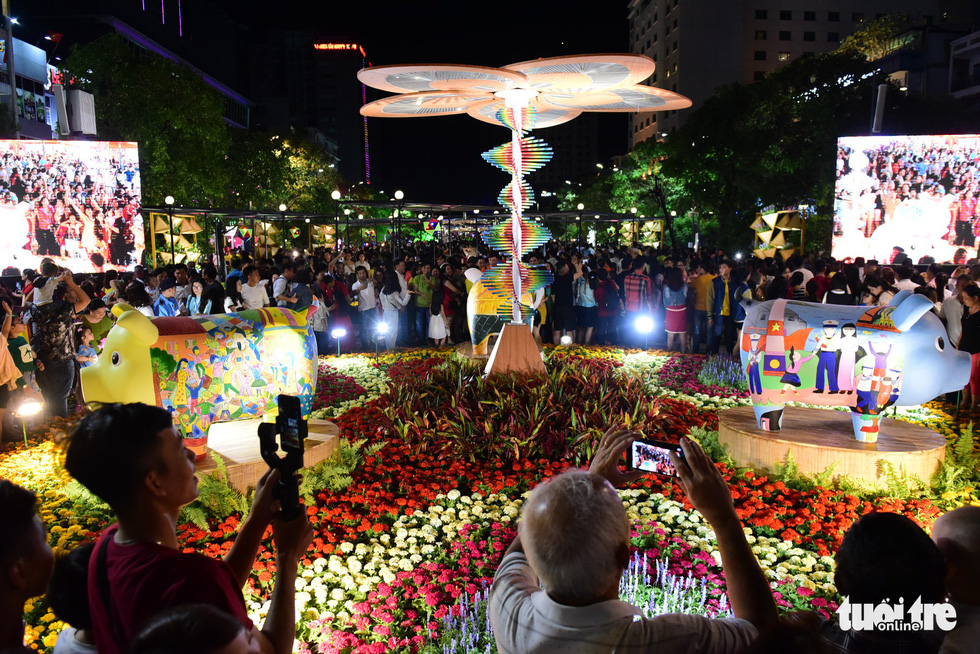 People walk next to flower-adorned structures in the Nguyen Hue Street Flower in Ho Chi Minh City, February 2, 2019. Photo: Quang Dinh / Tuoi Tre