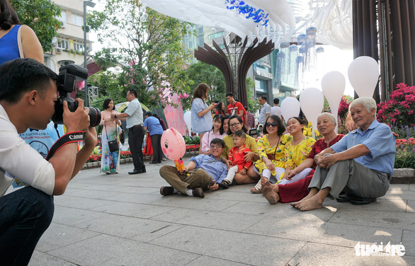 People take a group photo along Nguyen Hue Flower Street. Photo: Tuyet Kieu / Tuoi Tre