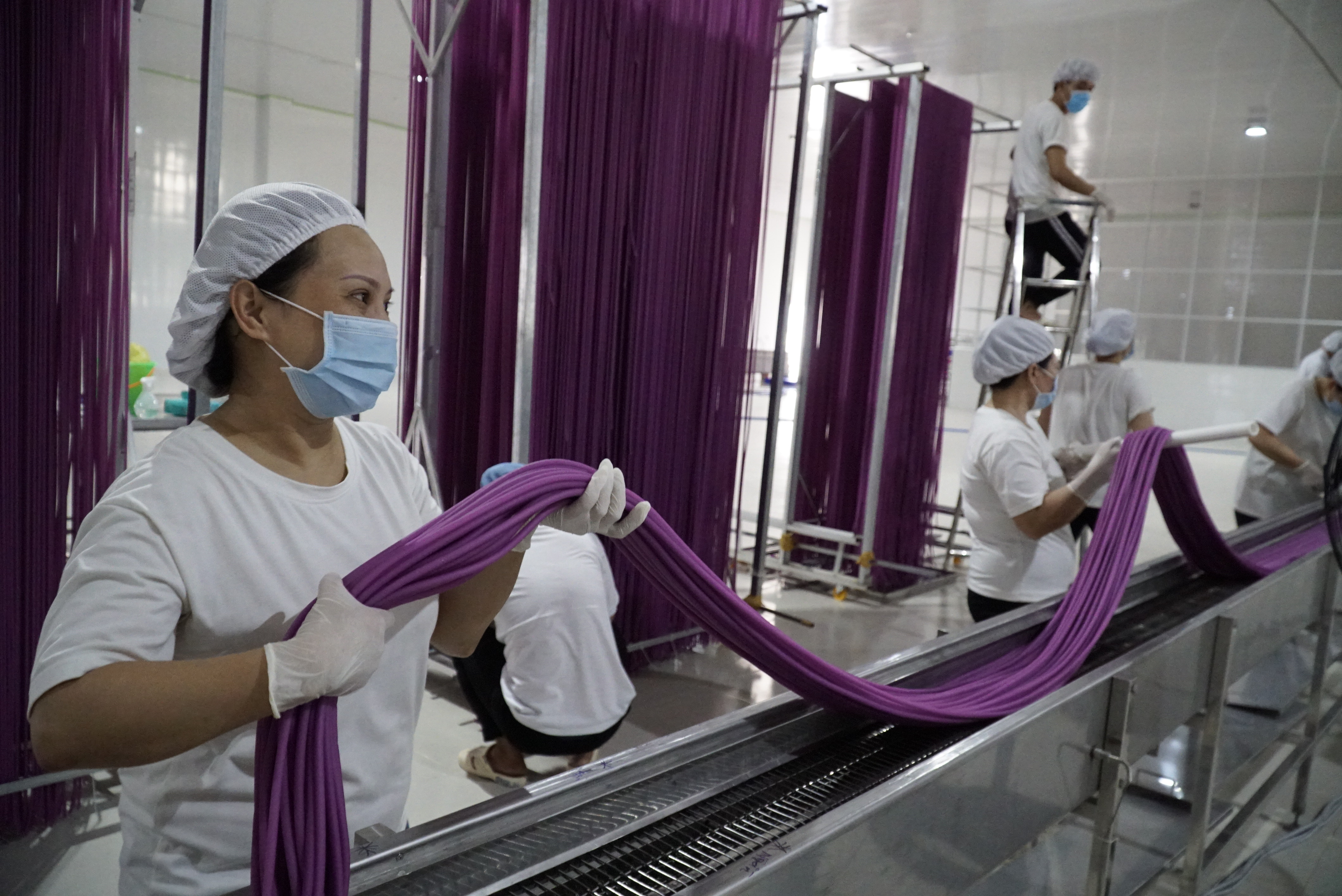 <em>Workers handle rice-flour straws at a plant in Sa Dec City, Dong Thap Province, Vietnam. Photo:</em> Ngoc Tai / Tuoi Tre