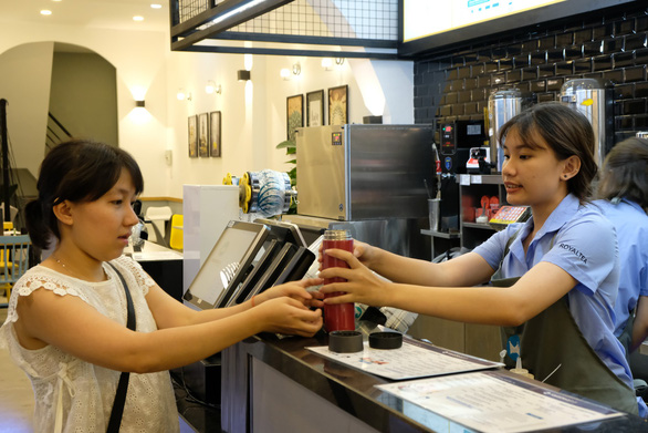A customer brings her own cup to buy bubble tea at a shop in Ho Chi Minh City. Photo: Vu Thuy / Tuoi Tre