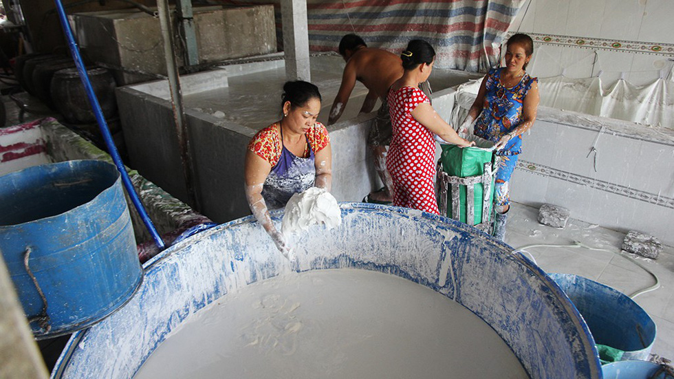 A worker takes raw flour from a container at the Sa Dec Flour Village in Dong Thap Province, southwestern Vietnam. This flour is then transported to neighboring food companies. Photo: C. Quoc, D. Phan & T. Nhon / Tuoi Tre