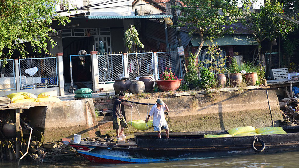 Men carry a bag of flour to a boat at the Sa Dec Flour Village in Dong Thap Province, southwestern Vietnam. Photo: C. Quoc, D. Phan & T. Nhon / Tuoi Tre