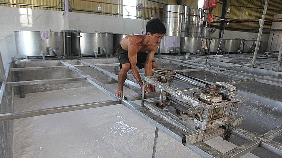 A worker pushes a machine that separates water from wet flour over a flour container at a workshop in the Sa Dec Flour Village in Dong Thap Province, southwestern Vietnam. The resultant product is called raw flour, which can be dried. Photo: C. Quoc, D. Phan & T. Nhon / Tuoi Tre