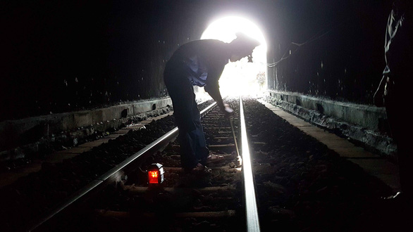 A patroller is tightening a loose screw on a tunnel track. Photo: Thai Loc / Tuoi Tre