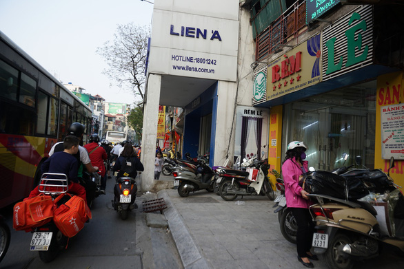 A store encroaches on the sidewalk and roadway along Ton Duc Thang Street.