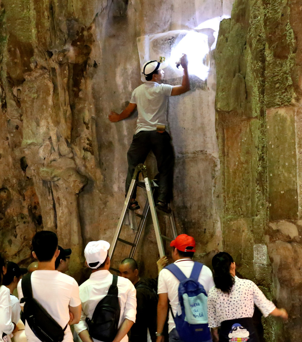 Tourists watch as researchers restore stone engravings at the Ngu Hanh Son Mountains in Da Nang. Photo: Nguyen Van Thinh / Tuoi Tre