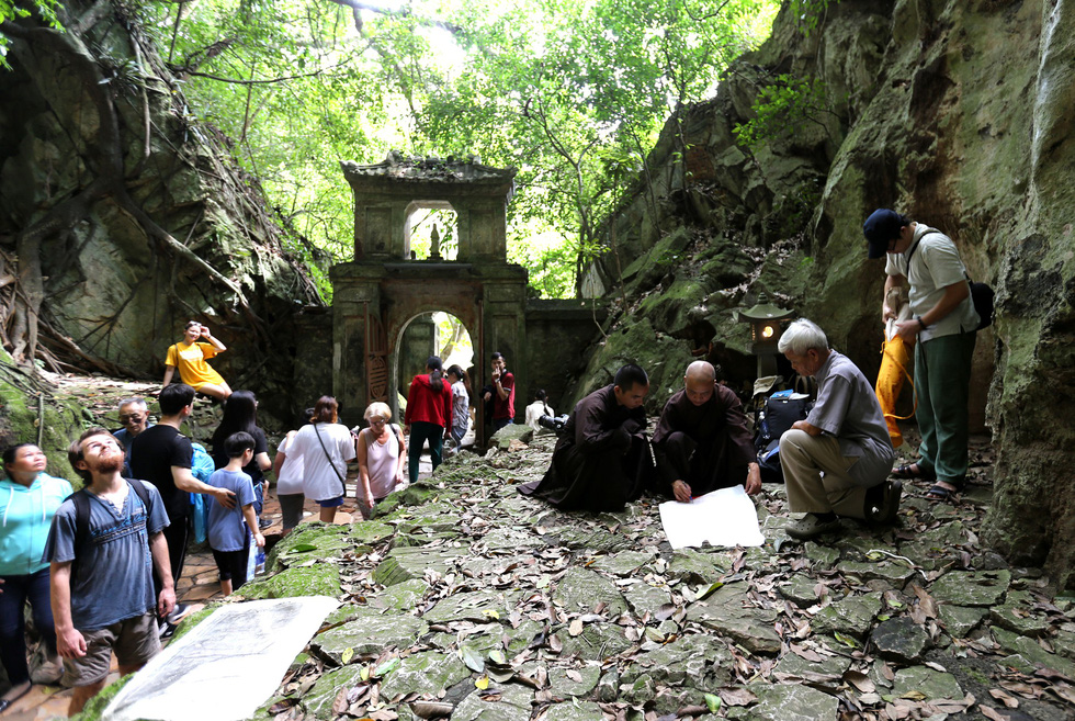 Tourists watch as researchers restore stone engravings at the Ngu Hanh Son Mountains in Da Nang. Photo: Nguyen Van Thinh / Tuoi Tre