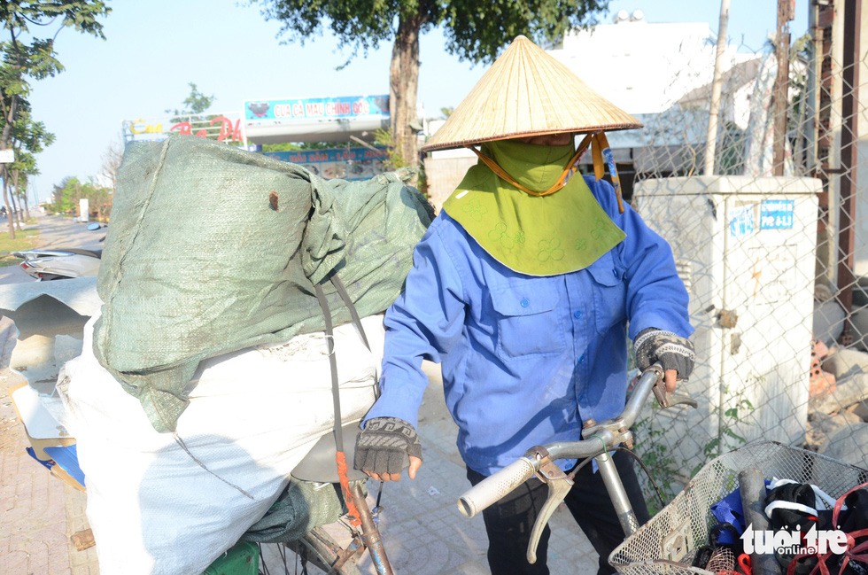 A female scrap dealer covers herself in coats and face masks when traveling on a street in Ho Chi Minh City. Photo: Uyen Trinh / Tuoi Tre