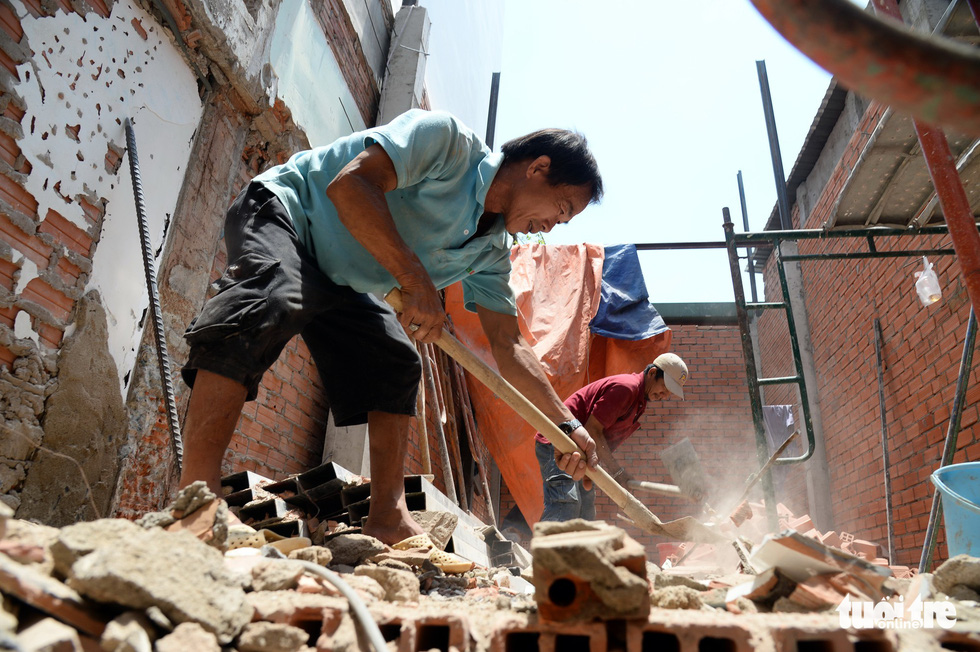 Two construction workers are pictured at a house demolition site in Ho Chi Minh City. Photo: Tu Trung / Tuoi Tre