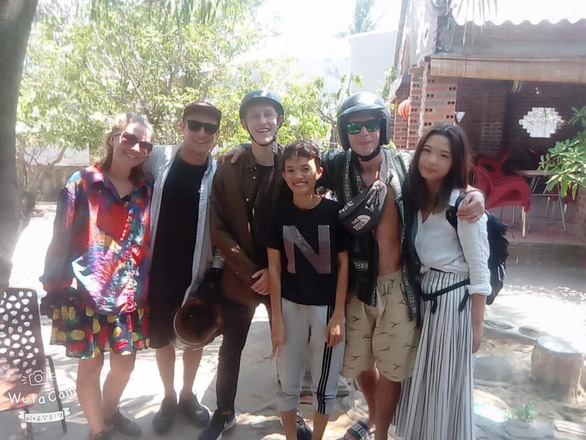 The British tourists take photos with locals after receiving their lost backpack from Thanh. Photo: Van To/ Tuoi Tre.