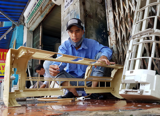A worker washes outdoor units of an air-conditioner. Photo: Ngoc Hien / Tuoi Tre