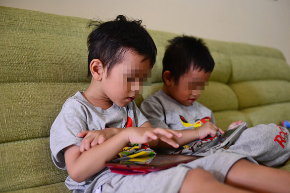 Two children glued to tablet screens. Photo: Quang Dinh / Tuoi Tre